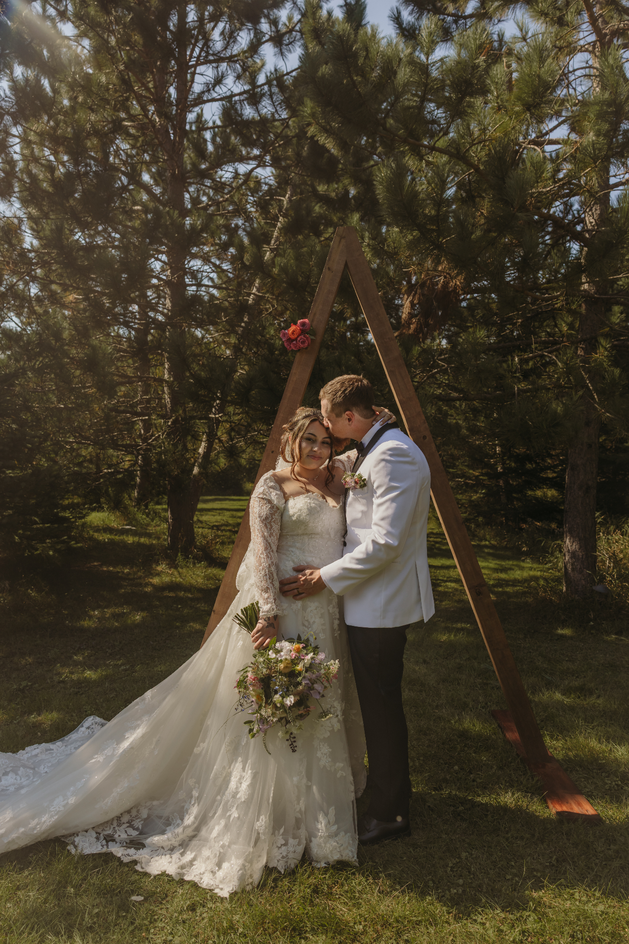 Couple under wooden arch at outdoor wedding