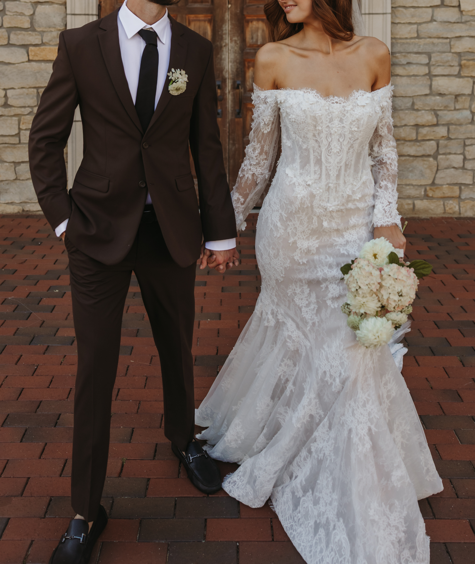 Bride and groom holding hands with bouquet
